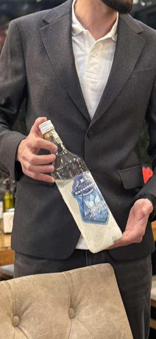 Handsome man holding a custom liquor bottle with cloth in a stylish setting.